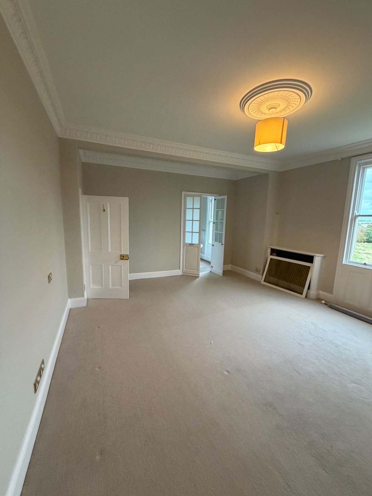Principal period room with neutral walls, white panelled doors and an illuminated ceiling rose