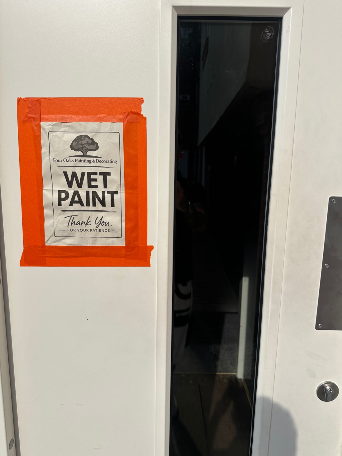 Four Oaks Painting & Decorating branded wet paint notice on a freshly finished communal door