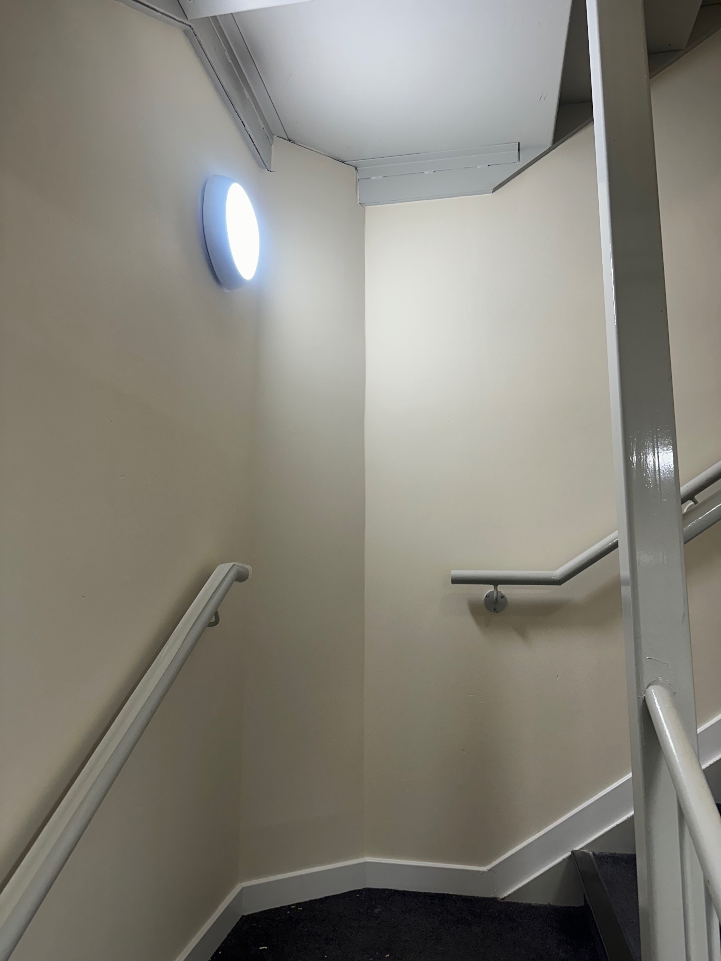 Half-landing wall and handrails freshly painted in cream and grey trade finish