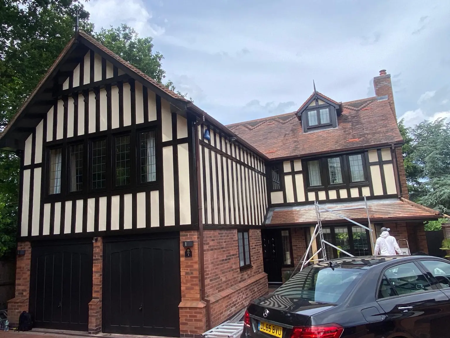 Tudor-Style Timber Frame Exterior Large Tudor-style detached house with dark timber framing, cream render panels and black garage doors after exterior decoration