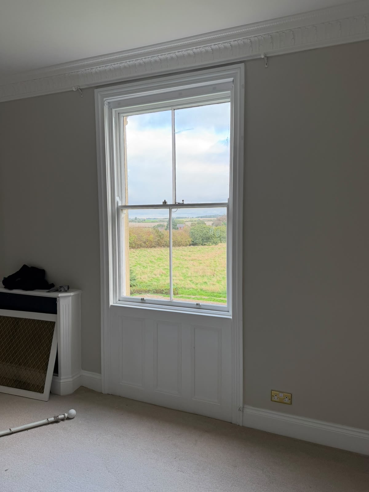 White sash-window surround and lower timber panelling with decorative cornice above