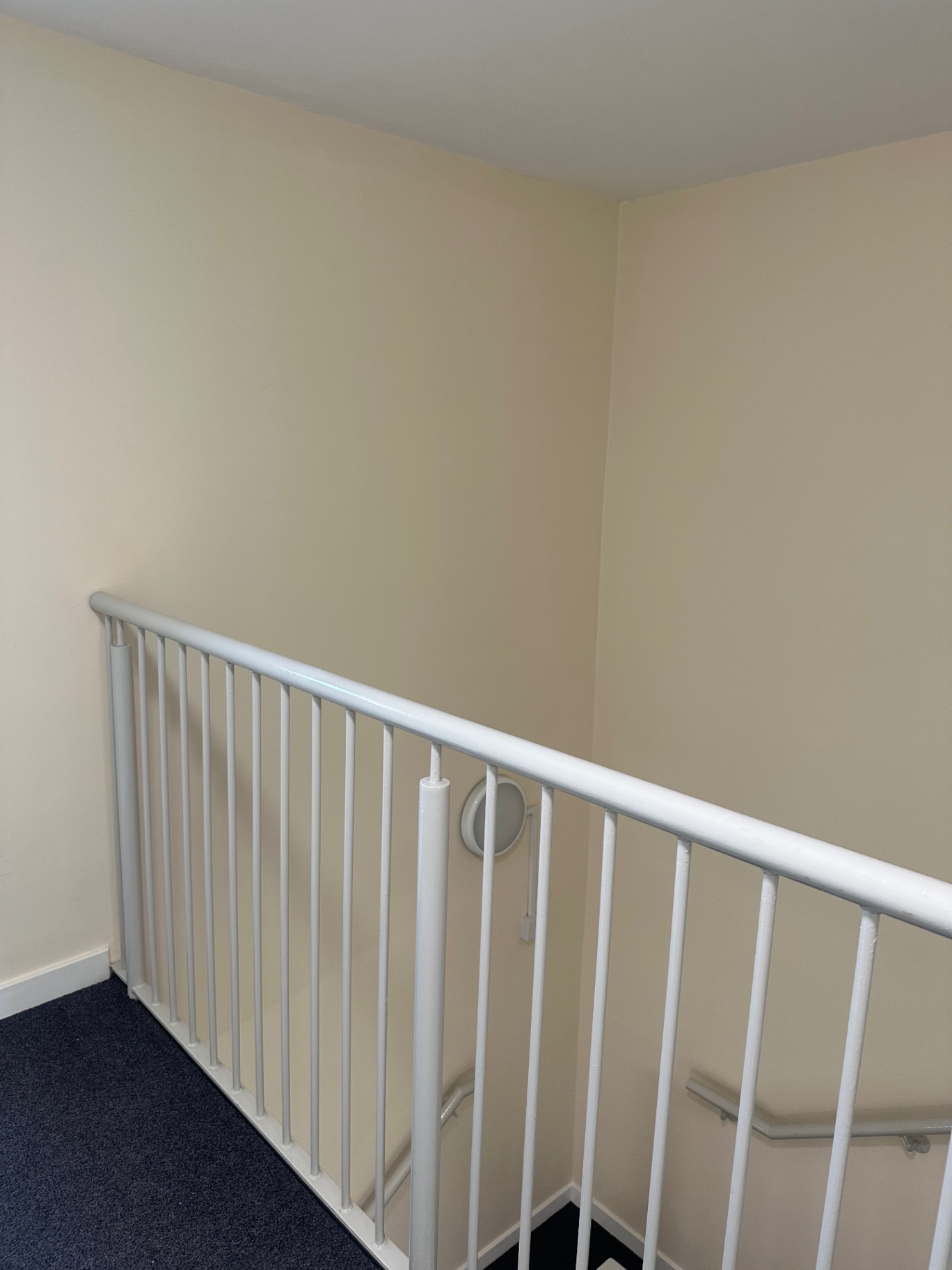 Top landing walls, ceiling and metal balustrade freshly redecorated in a communal stairwell