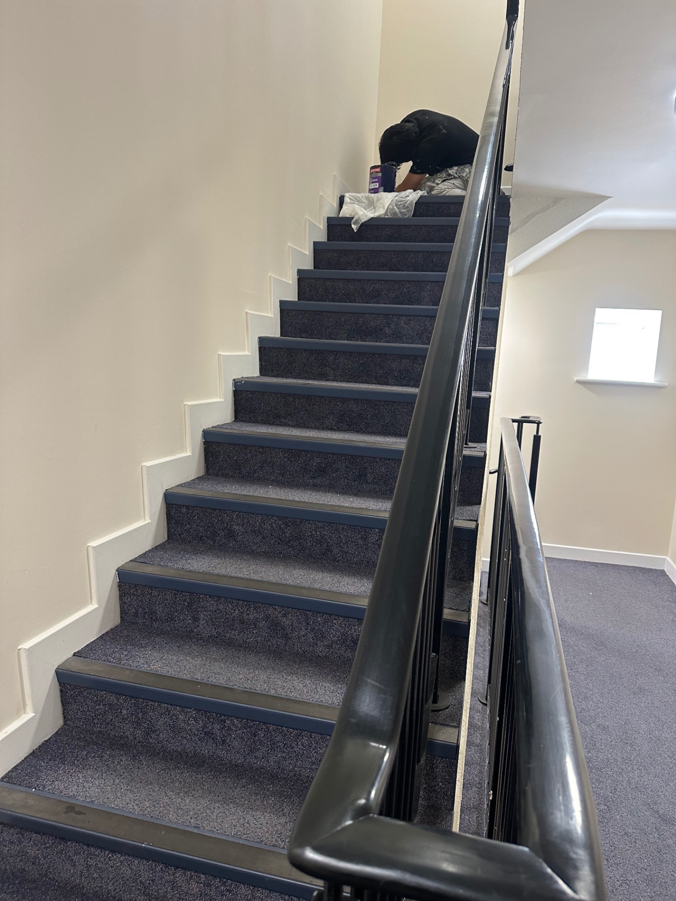 Communal staircase mid-flight — walls, spindles and metal balustrade fully redecorated