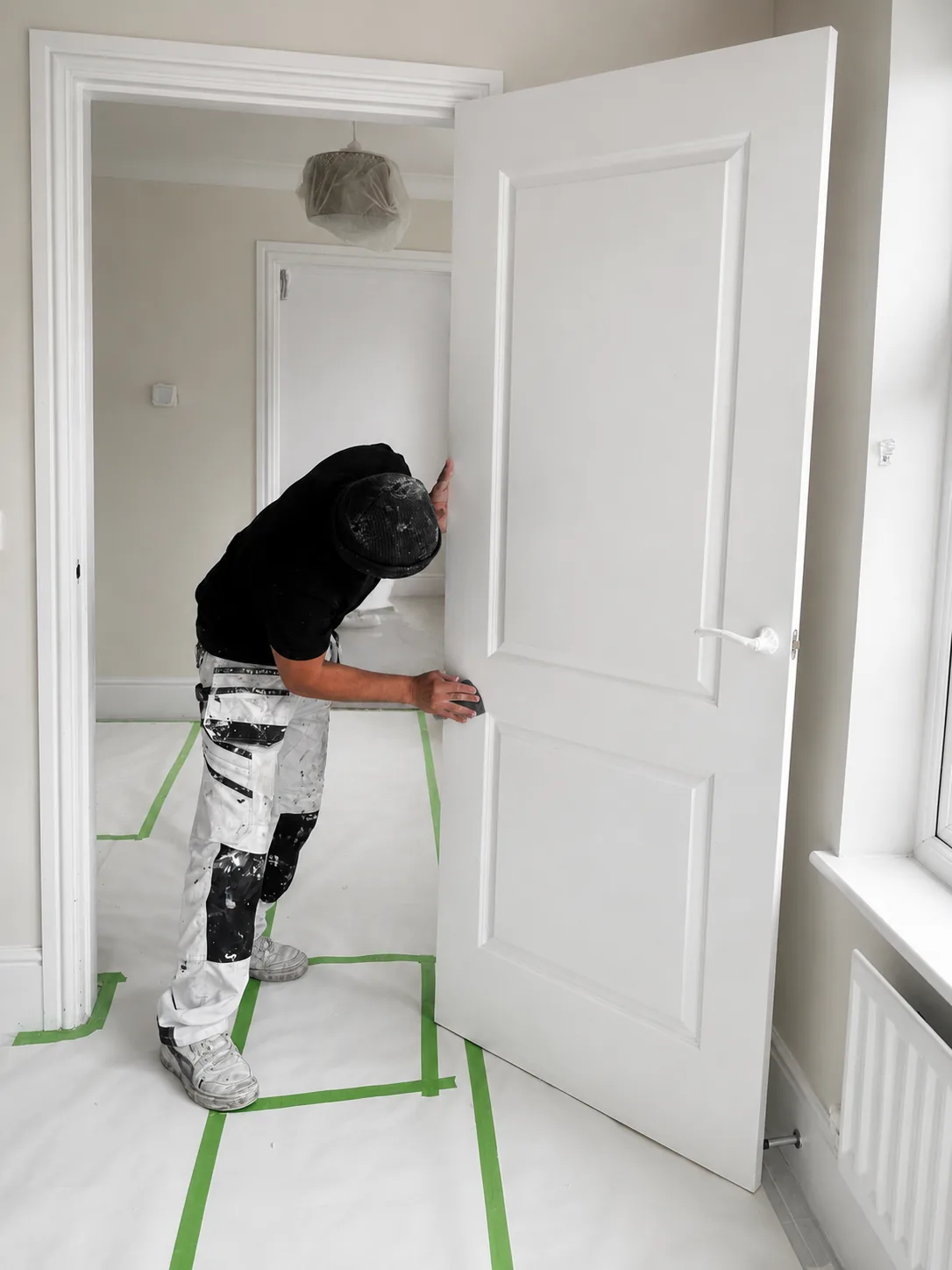 Four Oaks decorator preparing a freshly sprayed internal door on site